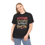 Black unisex heavy cotton t-shirt with "Attitude is Everything" design shown on a woman (front view)